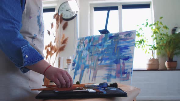 A Woman Paint Artist Drawing an Abstract Blue Painting with Brushes and Palette Knife