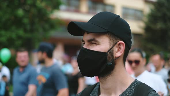 Portrait of Male Rebel Activist in Face Mask Marching in Protesting Riot Crowd