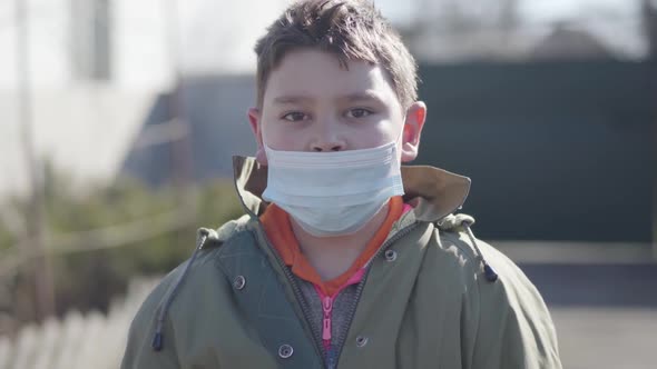 Portrait of Little Caucasian Brunette Boy in Face Mask Waving at Camera. Cute Child with Brown Eyes