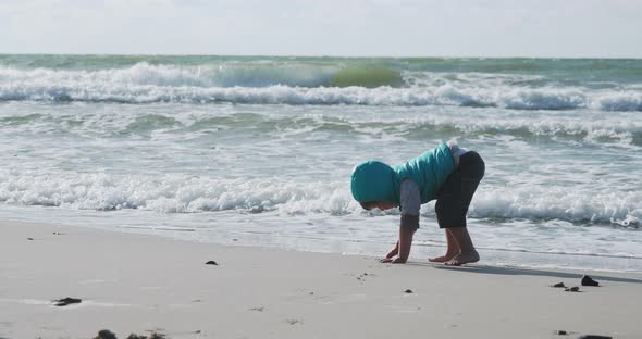 Toddler Boy in Waistcoat Is Playing with Sand on Sea Side.