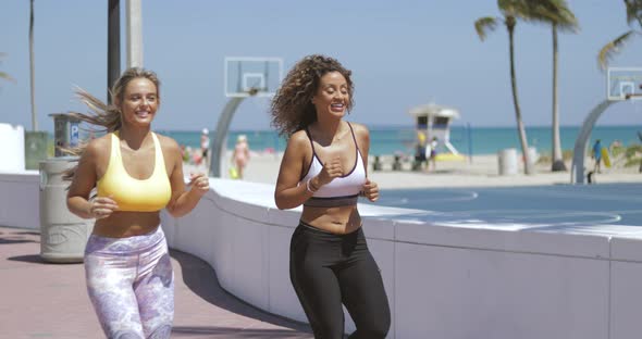 Sportive Women Running Together on Shore