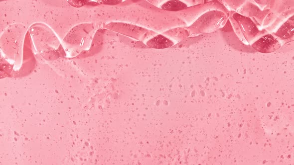 Pink Transparent Cosmetic Gel Fluid With Molecule Bubbles Flowing On The Plain White Surface