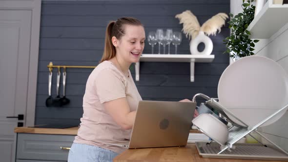 Woman Stands in the Kitchen and Communicates Via Video on Laptop