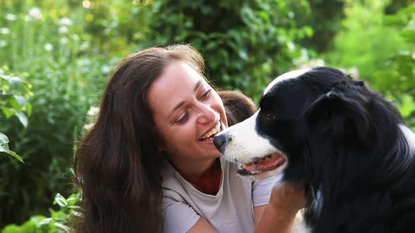 Smiling Young Attractive Woman Playing with Cute Puppy Dog Border Collie on Summer Outdoor