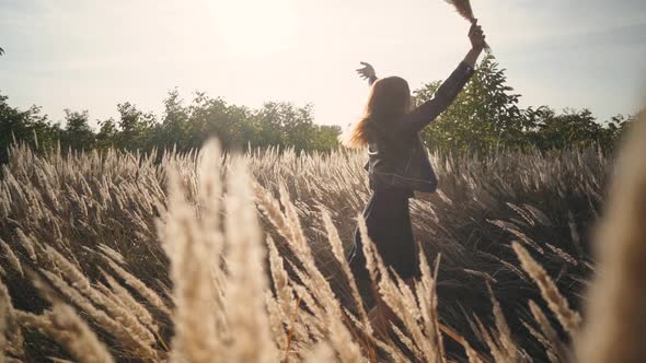 Beautiful Young Woman in the Field Spins with Flowers and Spikelets