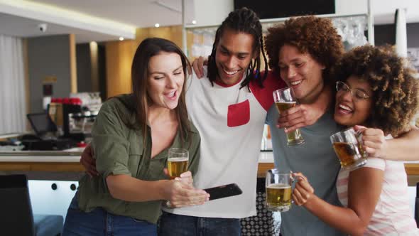 Diverse group of happy friends drinking beers and taking a selfie at a bar