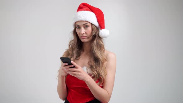 Woman Christmas Santa Hat White Studio Background with Smartphone in Hand