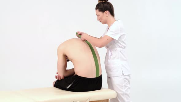 Physiotherapist sticks kinesio tapes to the back of patient, kinesiology taping, kinesiological 