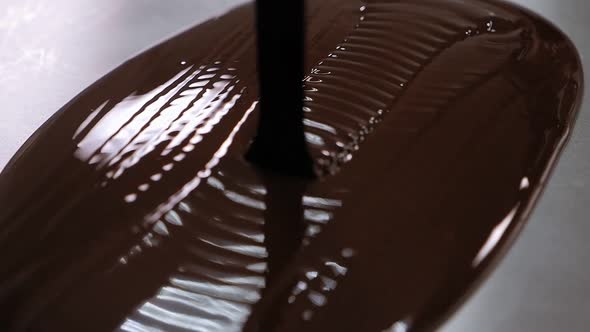 Close-up of Liquid Chocolate Pouring on a Metal Table in a Modern Pastry Shop.