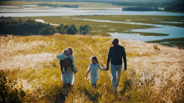 Family of Four Members Walking on the Path on Wheat Field