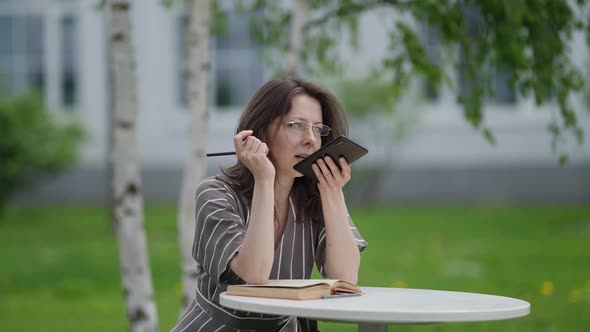 Female Student Searches for Information on the Subject with the Help of a Voice Assistant on the