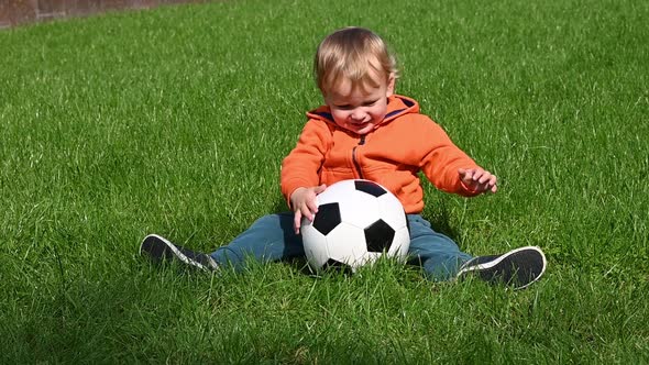 Little boy playing with football ball on grass