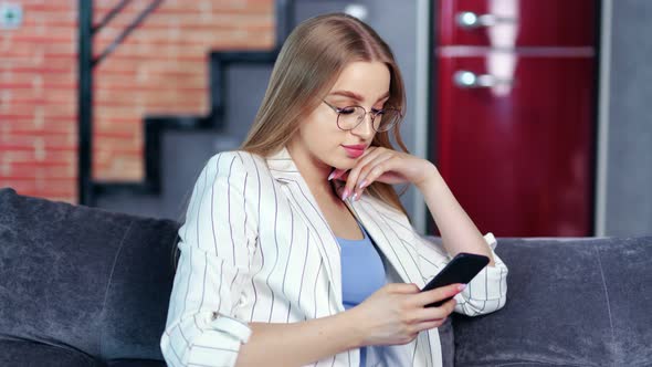 Busy Fashionable Young Girl Enjoying Chatting Typing Message Using Smartphone Sitting on Couch