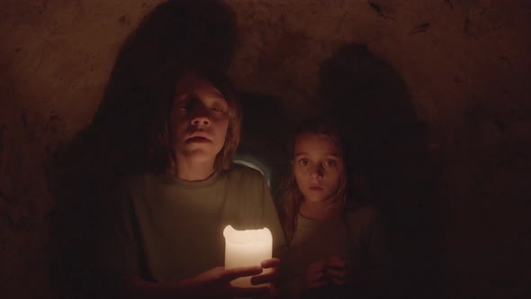 Medium Shot of Scared Kids Standing in Dark with Candle