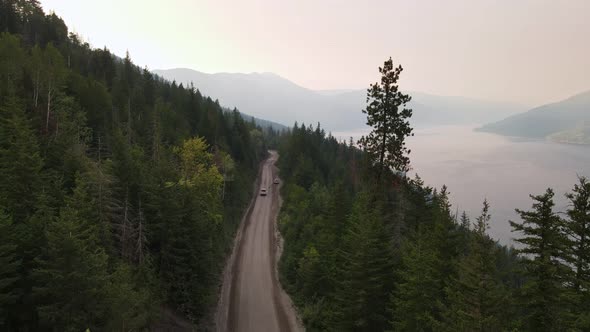 Pick-up truck passing a parked car along a dirt road that leads through British Columbia's vast coni