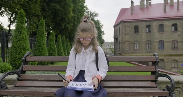 Girl Younger Schoolgirl with Glasses in School Uniform Writing Word Start