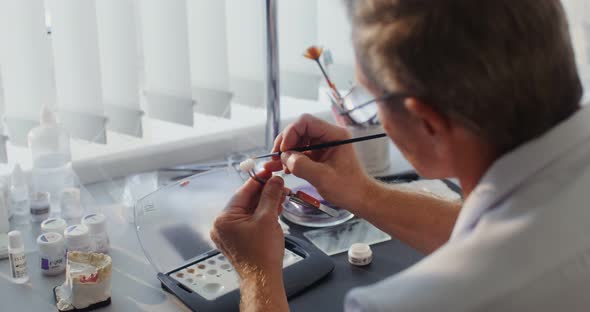 Closeup of Painting a Ceramic Dental Crown with a Thin Brush By Hand