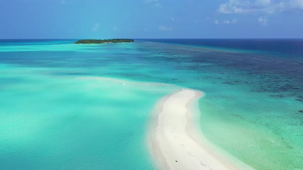 Wide angle flying copy space shot of a sandy white paradise beach and blue water background in vibrant