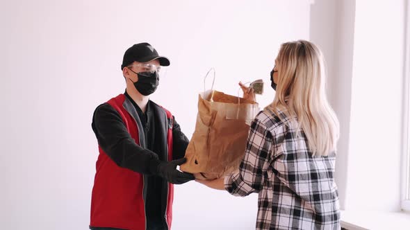 Deliveryman Is Diving a Craft Paper Bag To a Woman in Mask