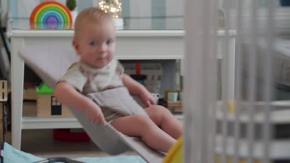 Adorable Baby Sitting in Infant Bouncer 10 Month Old Caucasian Kid Using Legs and Arm Muscles to