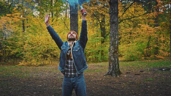 Male Tourist Standing in Autumn Forest with Blue Signal Fire Tracking Shot