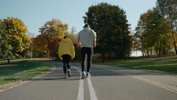 Man and Woman Start Running on a Track at Park in Autumn Talking and Smiling