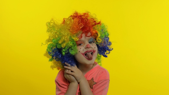 Little Child Girl Clown in Wig Making Silly Faces. Having Fun, Smiling, Showing Tongue. Halloween