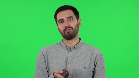 Portrait of Brunette Guy with TV Remote in His Hand, Switching on TV. Green Screen