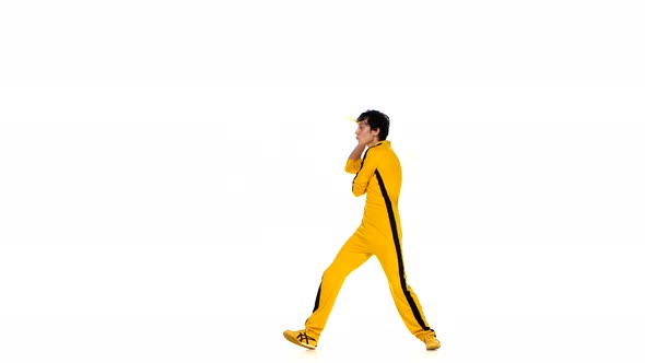 Man in Yellow Suit Training Karate and Expertly Twirling Nunchaku