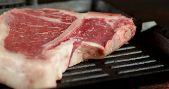 Steak T-bone Raw Beef in a Frying Pan Slowly Rotates 