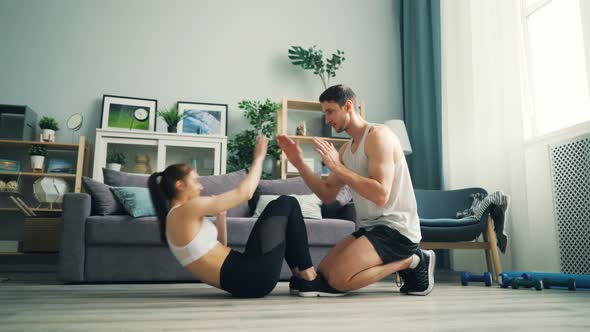 Young People Man and Woman Doing Situps and Clapping Hands Training at Home