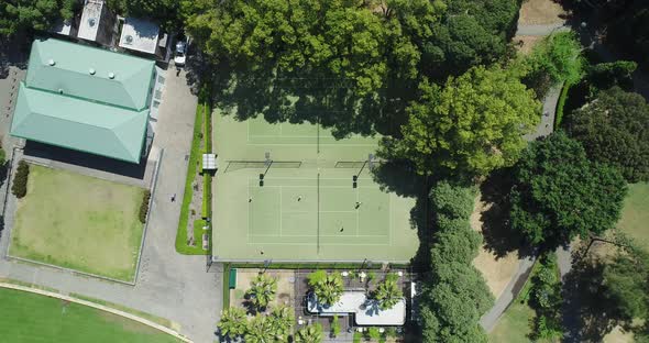 Static aerial shot looking directly down on tennis court as people play.