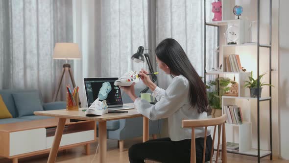 Footwear Designer Looking At A Laptop And Putting Coloured Unique Patterns On Sneakers At Home