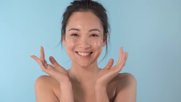 Model applying cream on the cheeks.