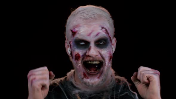 Frightening Man with Halloween Zombie Makeup Wearing Earphones Listening Music Dancing Celebrating