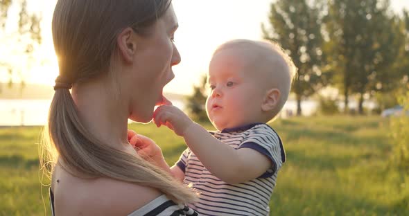 Close View of Cute Smiling Toddler Plays with His Mother While She Holds Him