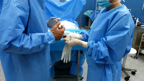 Nurse helping a surgeon in wearing surgical gloves