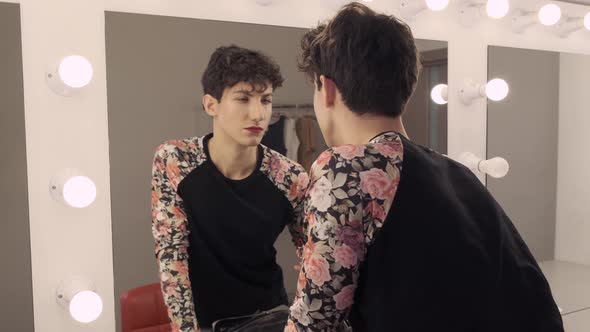 Androgynous Man Holding Lipstick in His Hands and Paints Lips