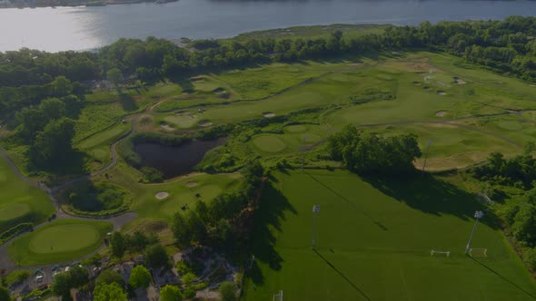 Forward Aerial Shot of a Golf Course by the Water on a Sunny Day