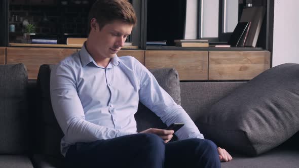 Handsome Man Using Smartphone in Living Room.