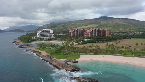Aerial dolly shot along coastal lagoons with luxury resorts in the background on the island of O'ahu