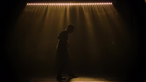 Silhouette of a Young Guy Playing on the Electric Guitar on Stage in a Dark Studio with Smoke and