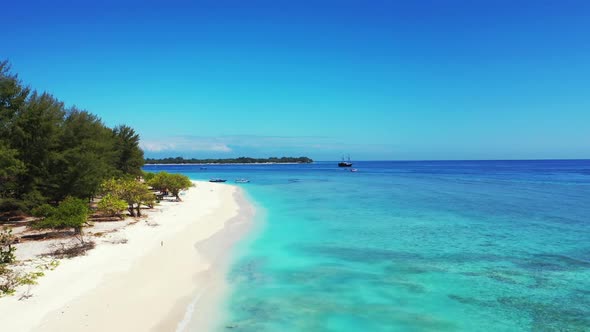 Aerial drone view seascape of tranquil tourist beach vacation by blue lagoon with bright sand backgr