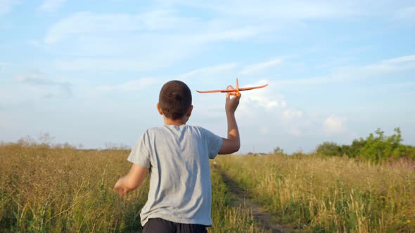 Unrecognizable Boy Runs Across the Field and Plays with a Small Plane