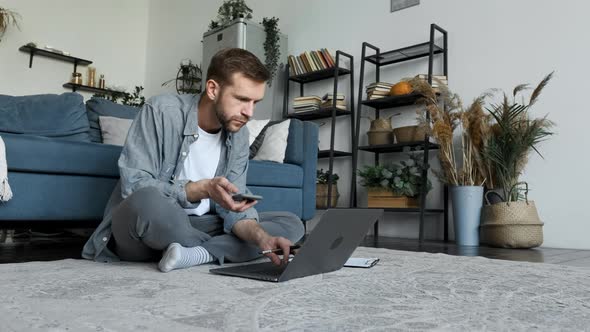 A Young Freelance Man Works At Home and Uses A Laptop Computer, Looks at The Monitor Screen