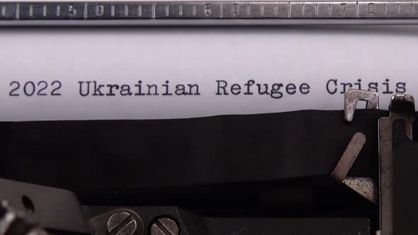 Typing phrase "2022 Ukrainian Refugee Crisis" on retro typewriter.