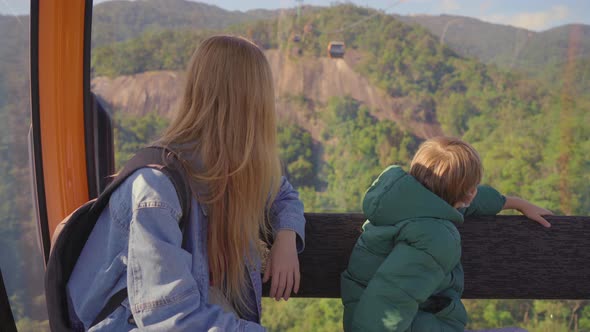 A Woman and Her Son Ride in a Cable Car Up the Mountain To the Ba Na Hills Resort in the City of