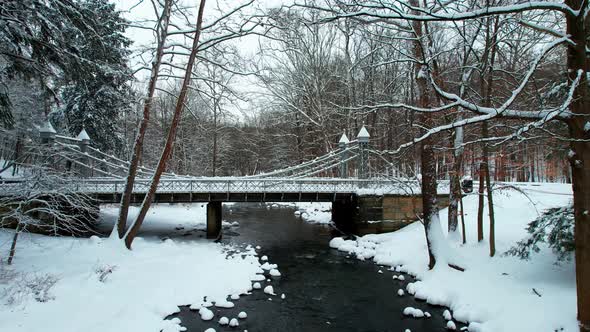 Winter landscape of small bridge covered in snow in winter forest