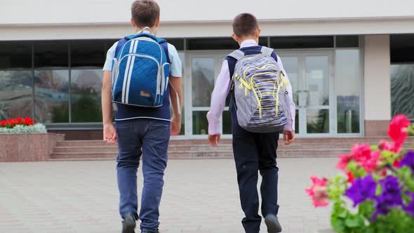 Schoolboys with Large Backpacks Walk To School Building