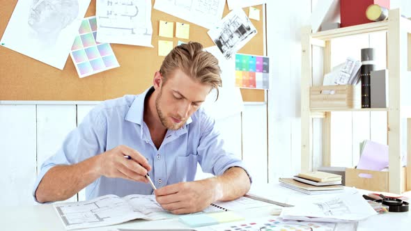 Young Confident Architector Checking Drawings Sitting at Workplace